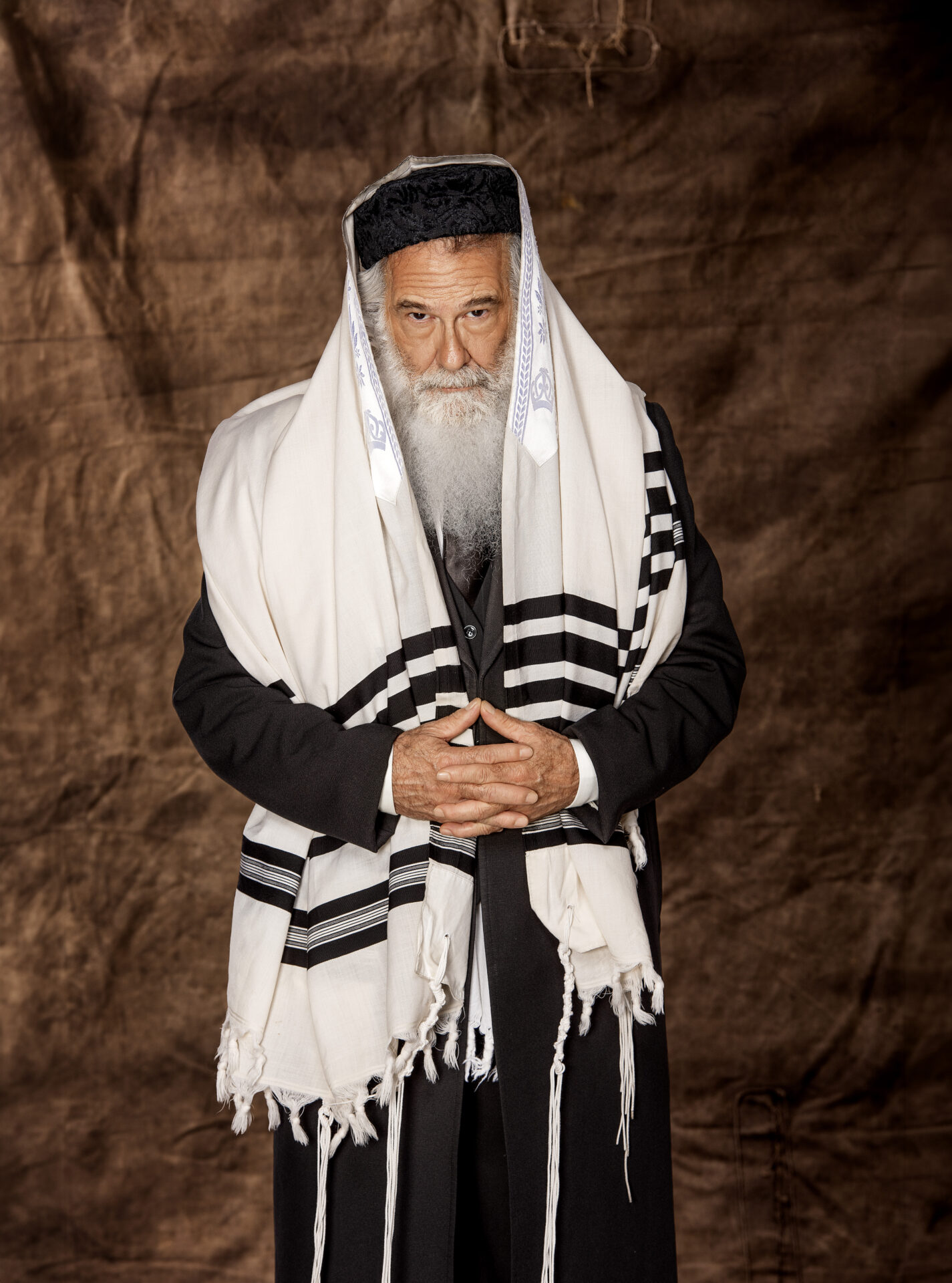 Personagem masculino de Dibuk, o Musical, usando talit e traje escuro