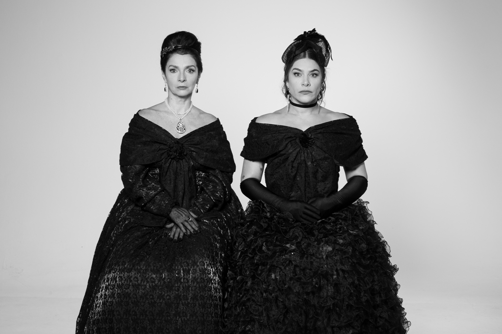 Claudia Ohana e Priscila Fantin de pé, lado a lado, olhando diretamente para a câmera, em As Amantes de George Washington