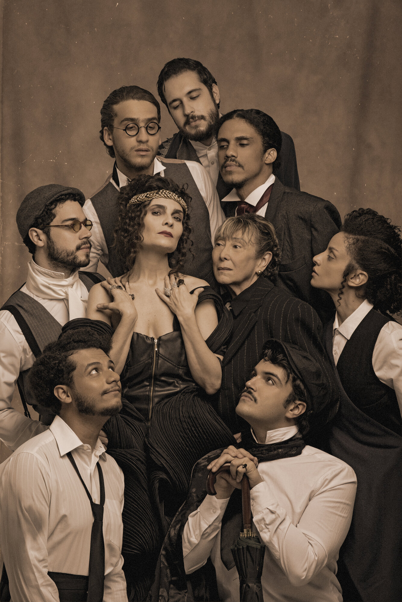 O elenco de nove reunido em torno da atriz que faz Sarah Bernhardt, em figurino de época, em fotografia de tom sépia
