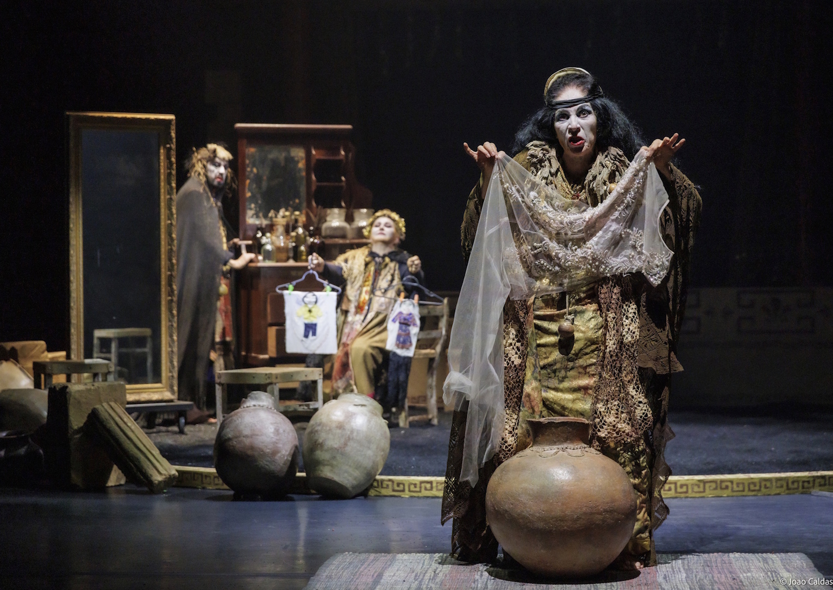 Medea em primeiro plano com o dispositivo de cena ao fundo