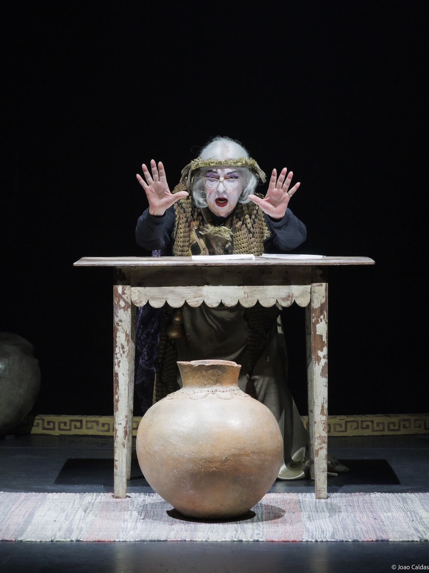 Walderez de Barros em cena, sentada à mesa, com o texto à frente