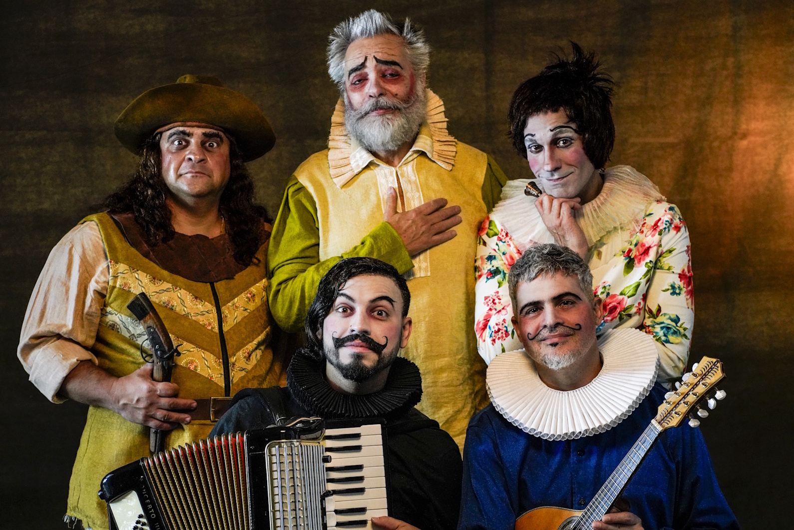 Cinco artistas caracterizados com figurinos de época, incluindo instrumentos musicais, posando em retrato de conjunto.