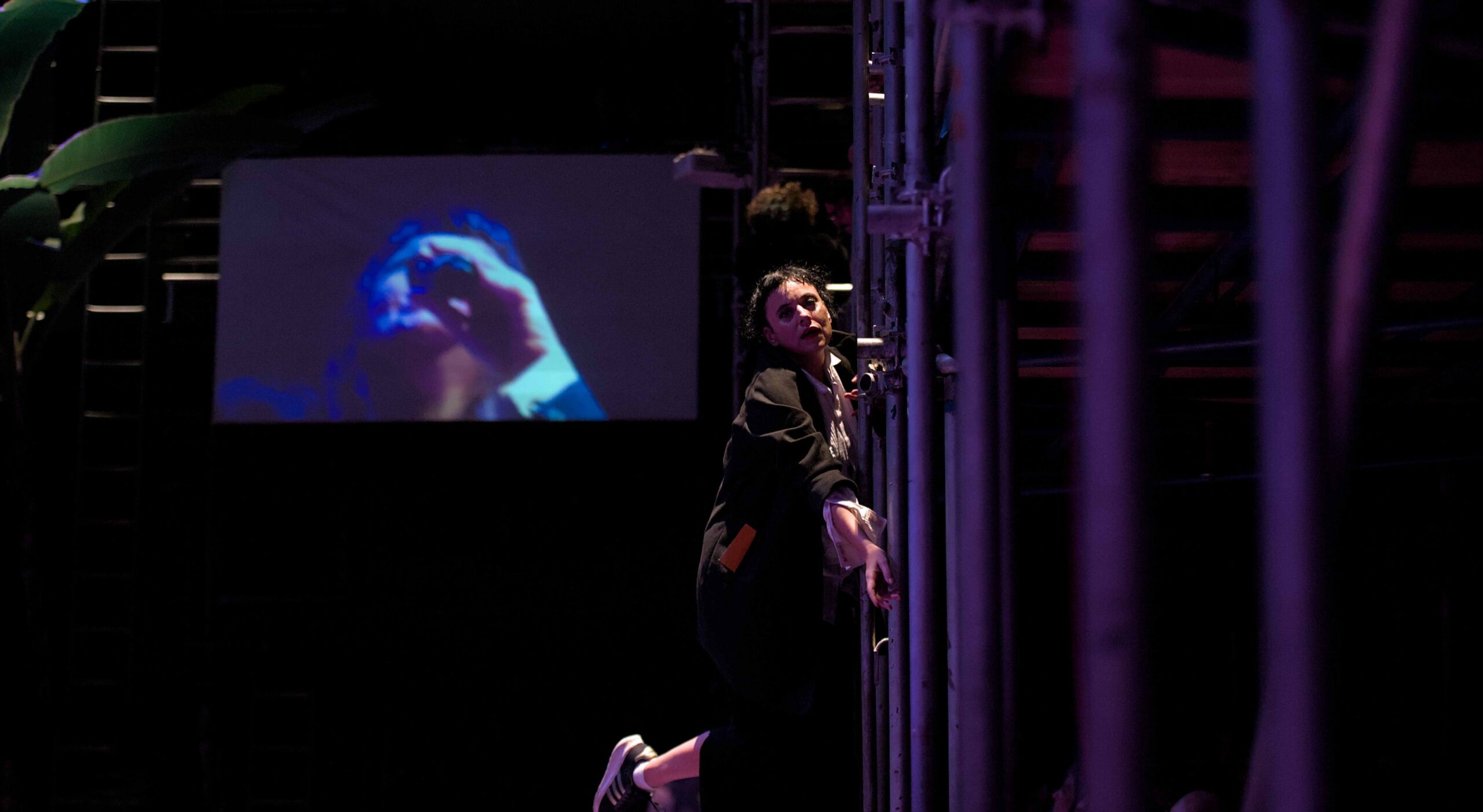 Cena com arquitetura do espaço cênico e performer em composição de risco.