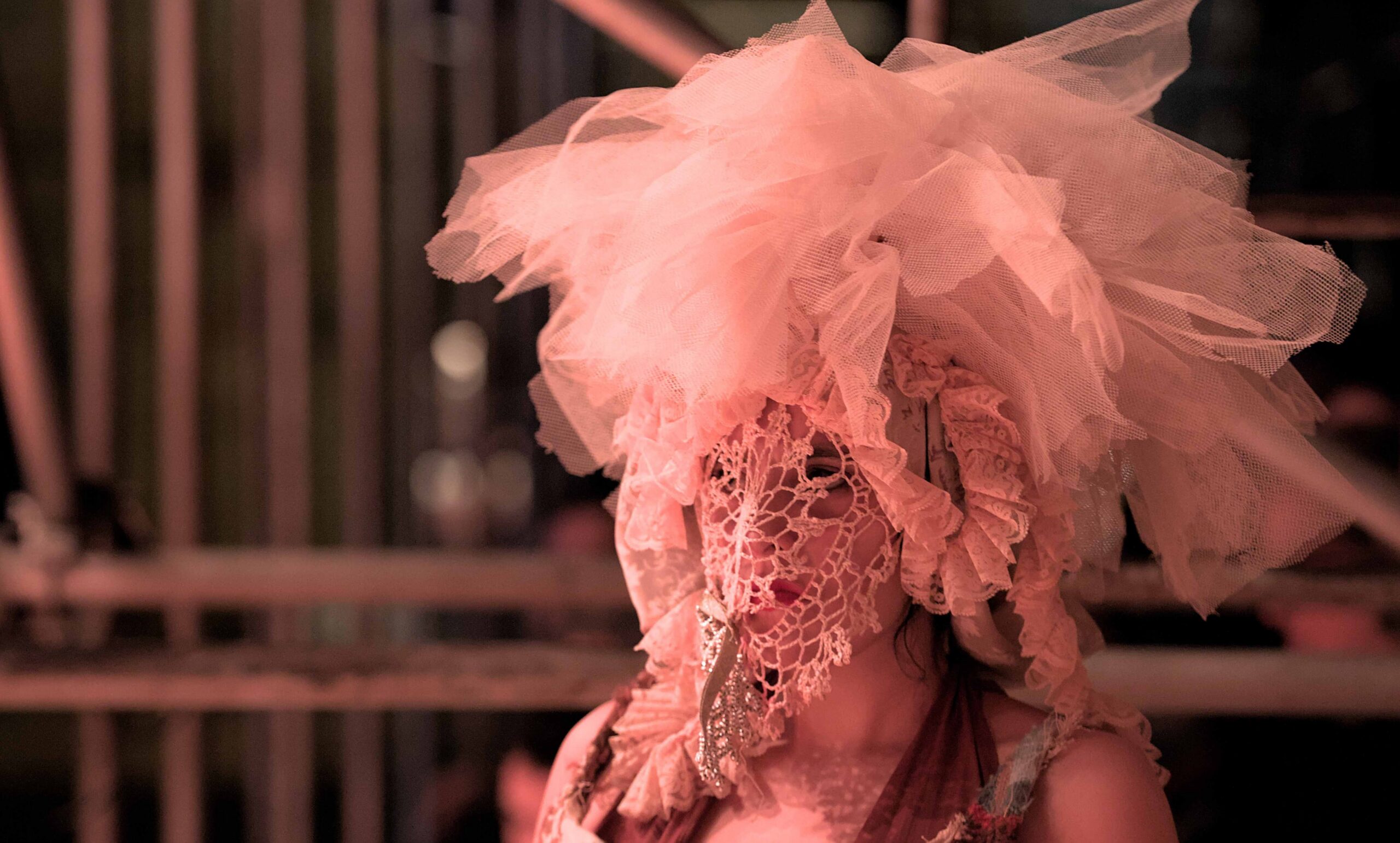 Detalhe de cena com máscara/figurino em luz intensa.